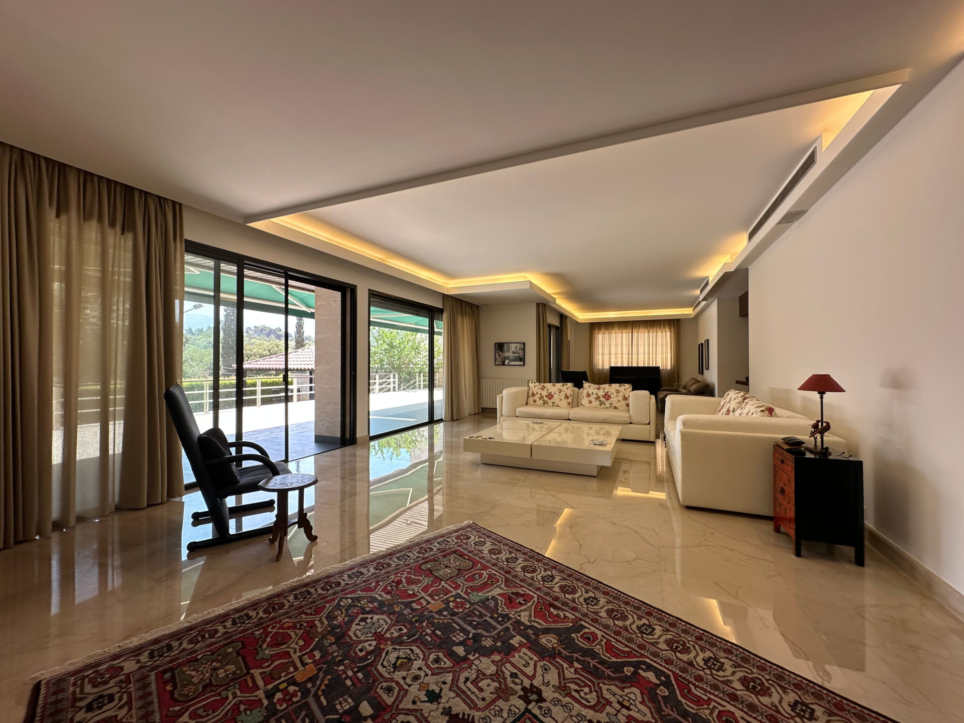 Refurbished reception room with polished marble flooring and recessed cove lighting