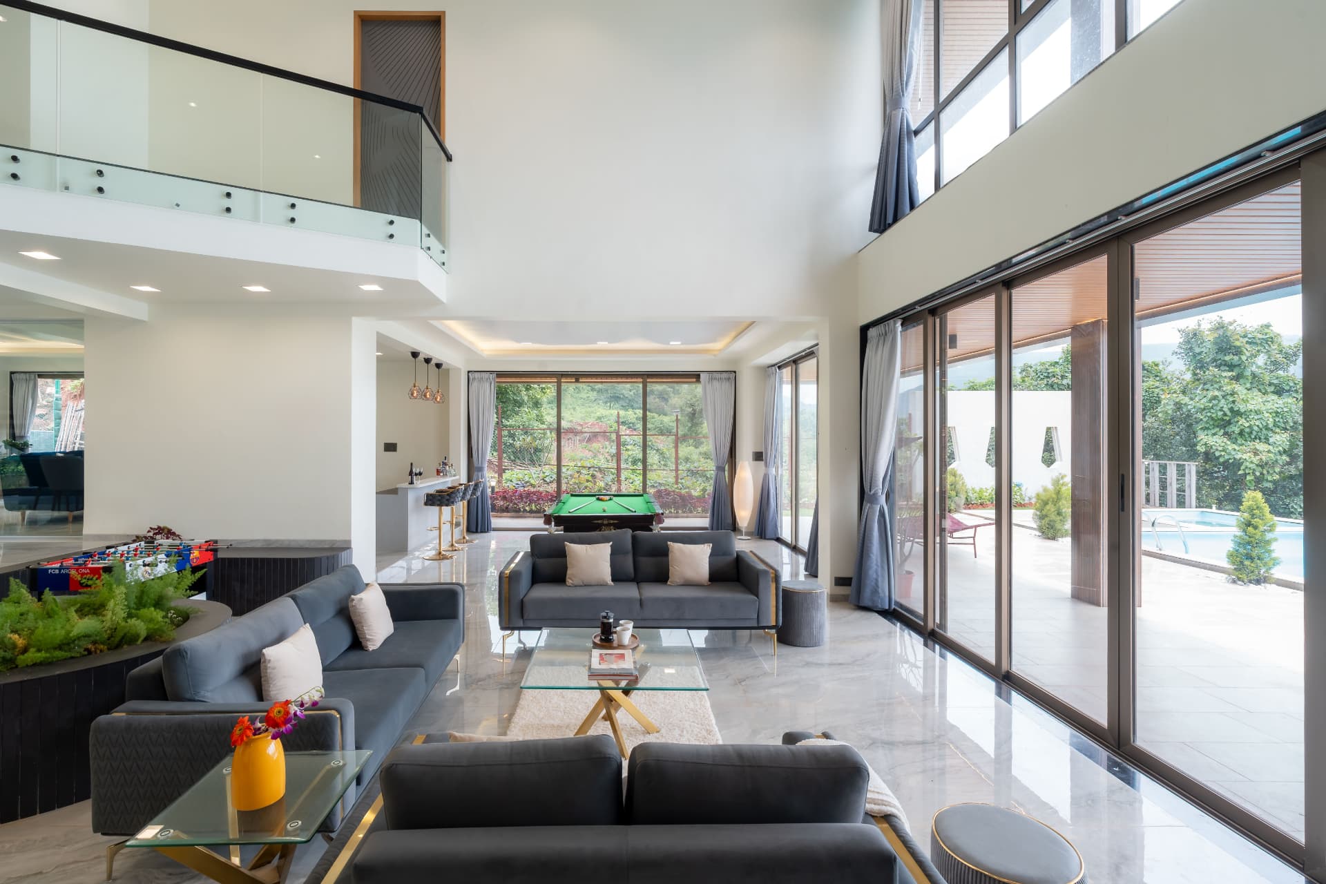 Double height family living room with glazed balustrade and marble flooring