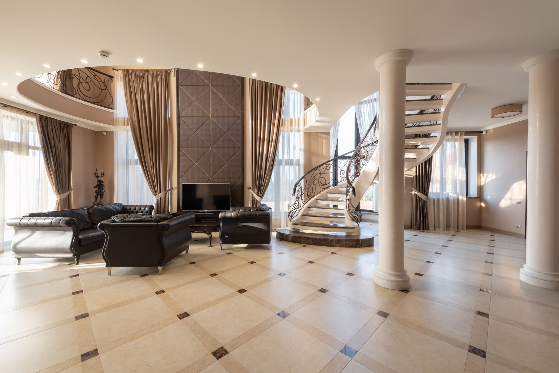 Reception hall with sweeping stone staircase, columns and inlaid marble floor