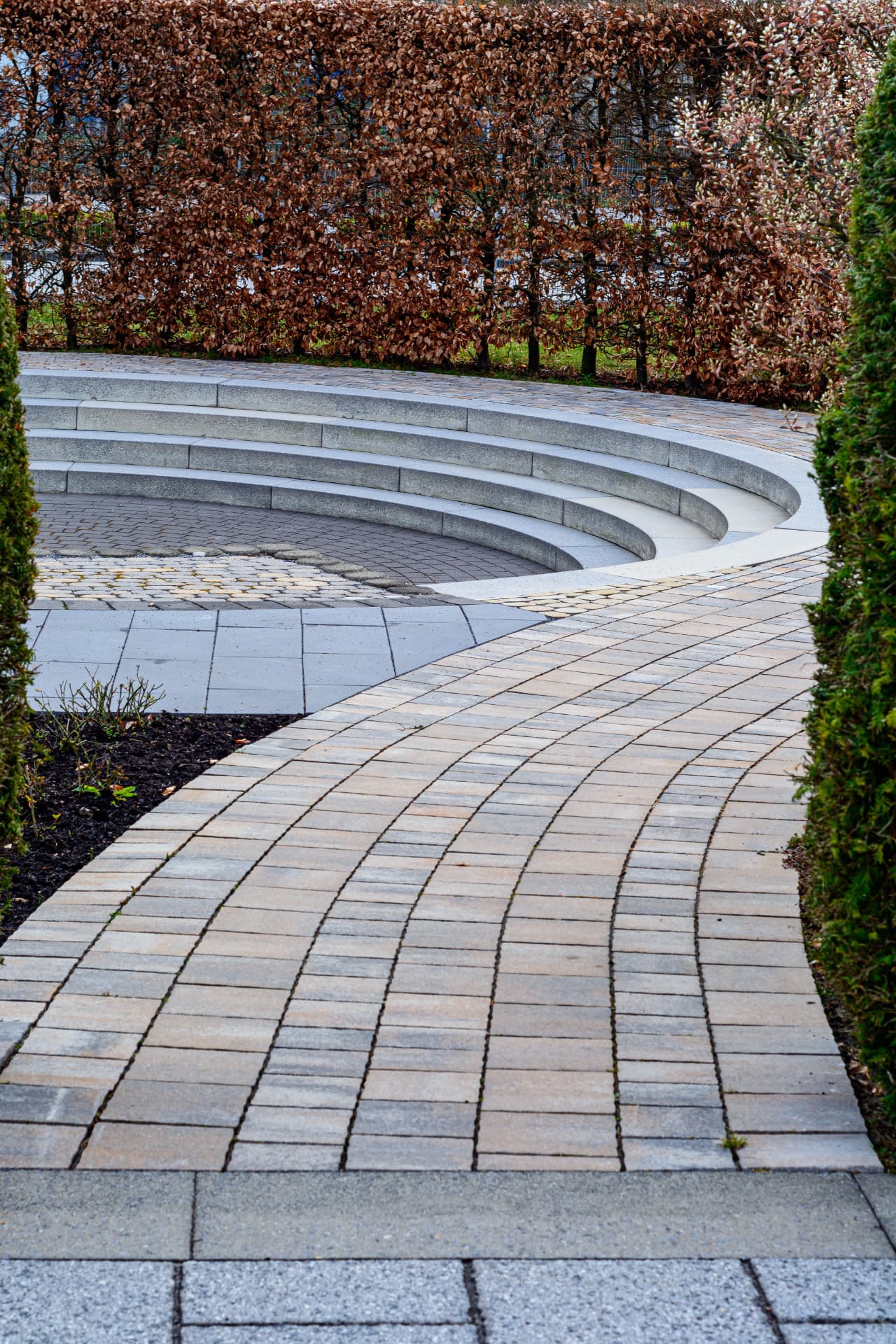 Curved block paved walkway with radial granite steps and clipped beech hedging
