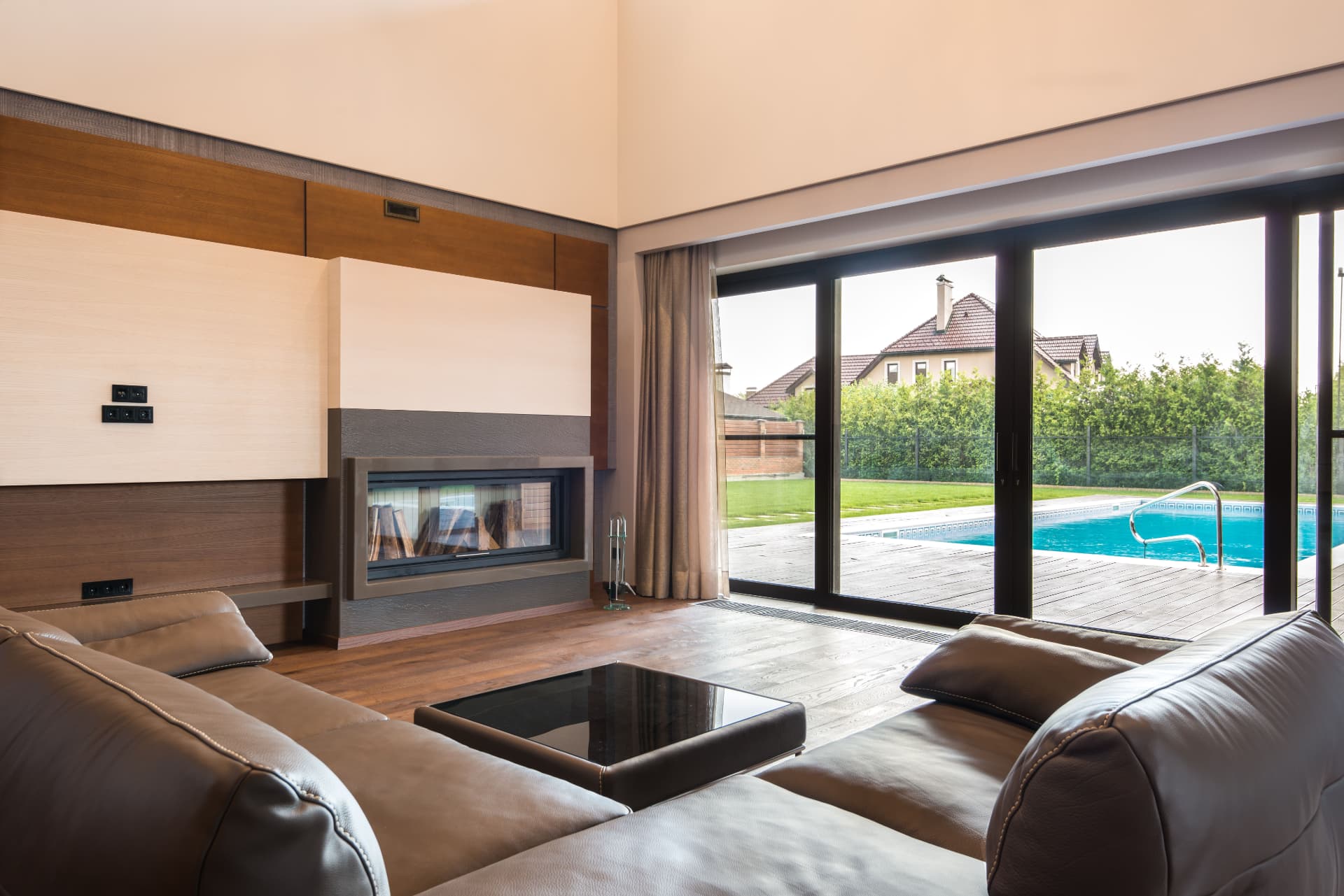 Living room with inset fireplace and full height glazing onto the pool terrace
