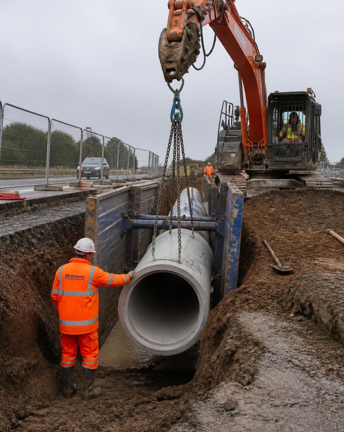 Large diameter drainage pipe lowered into a shored trench