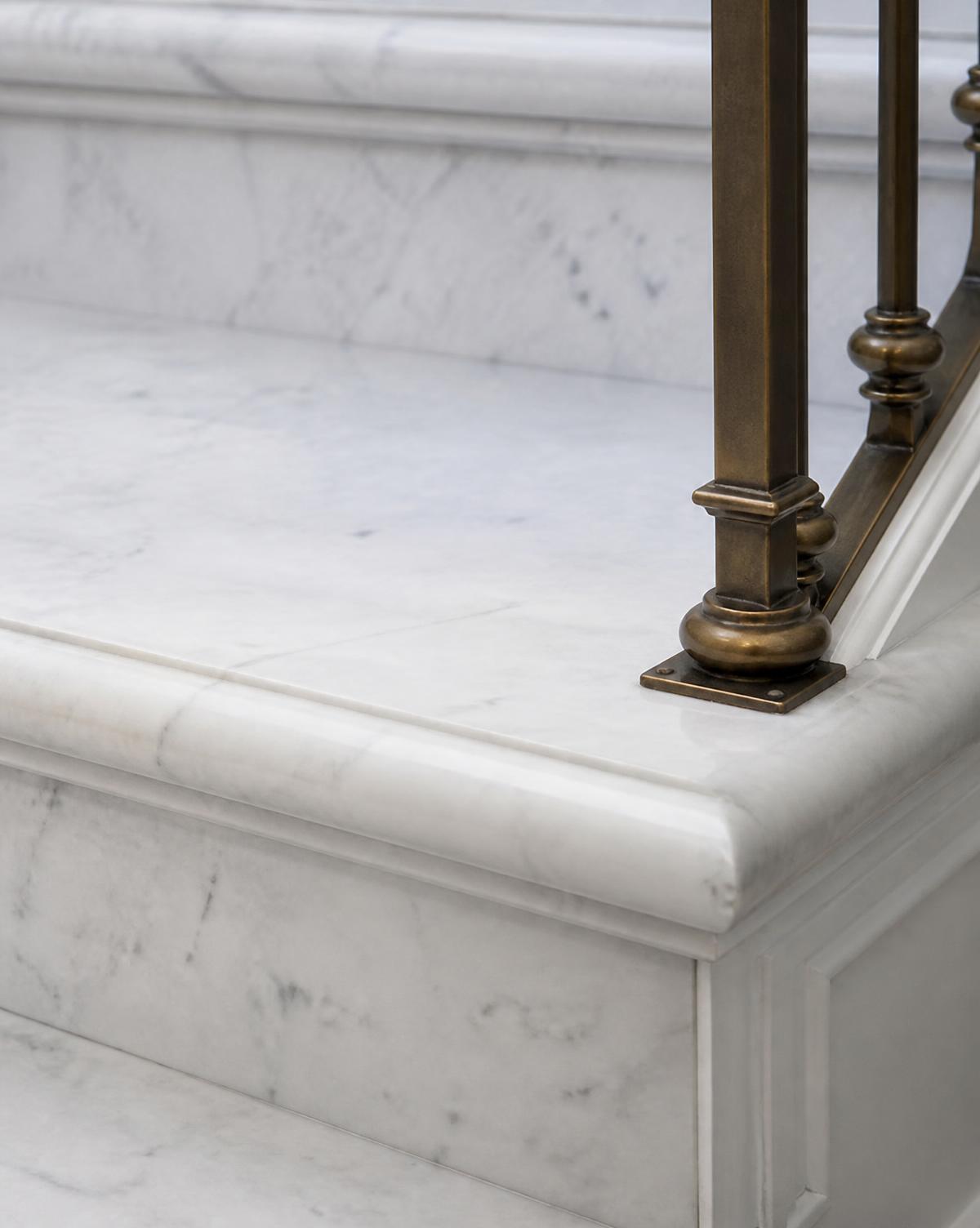 Detail of the solid marble tread nosing and bronze fixing